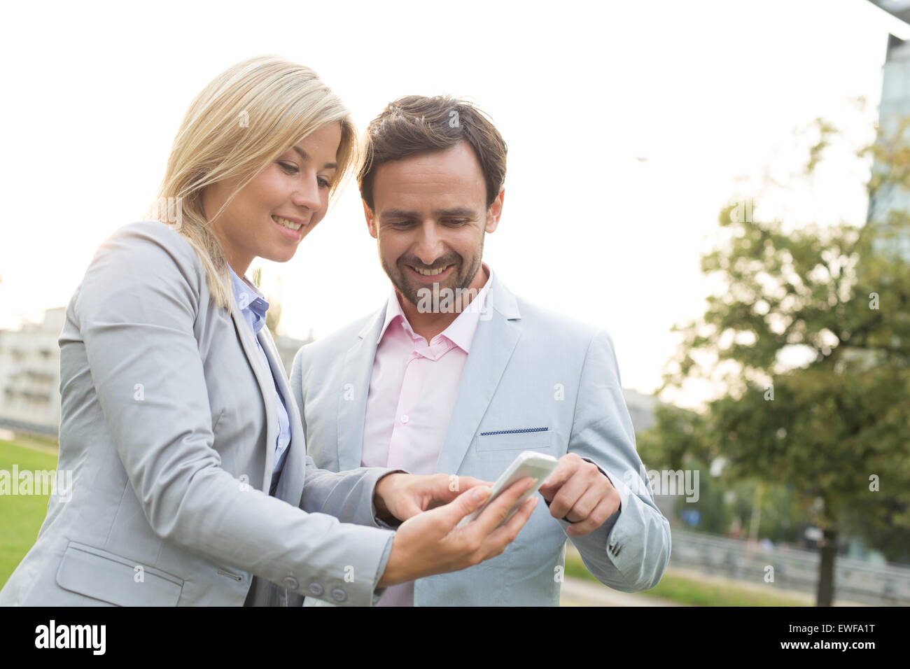 Happy business couple using smart phone at park Banque D'Images
