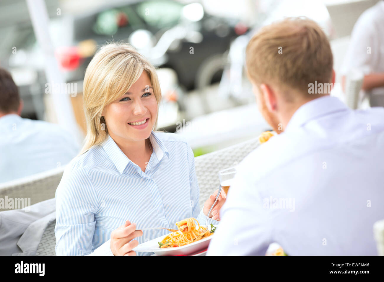 Happy businesswoman having food with male colleague at outdoor restaurant Banque D'Images