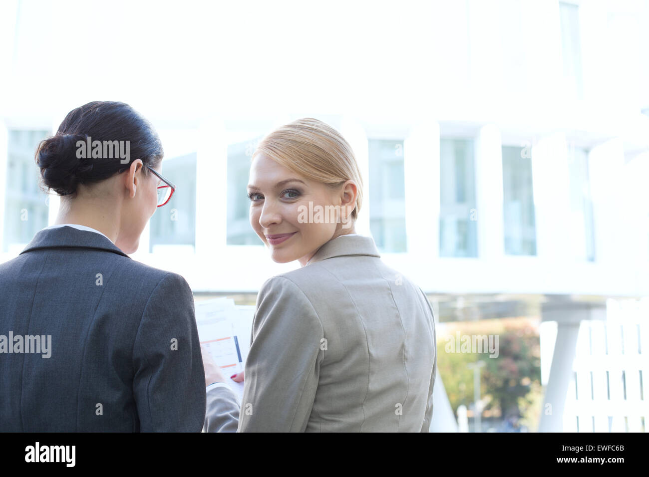 Vue arrière du portrait of smiling businesswoman sitting avec son collègue à l'extérieur Banque D'Images