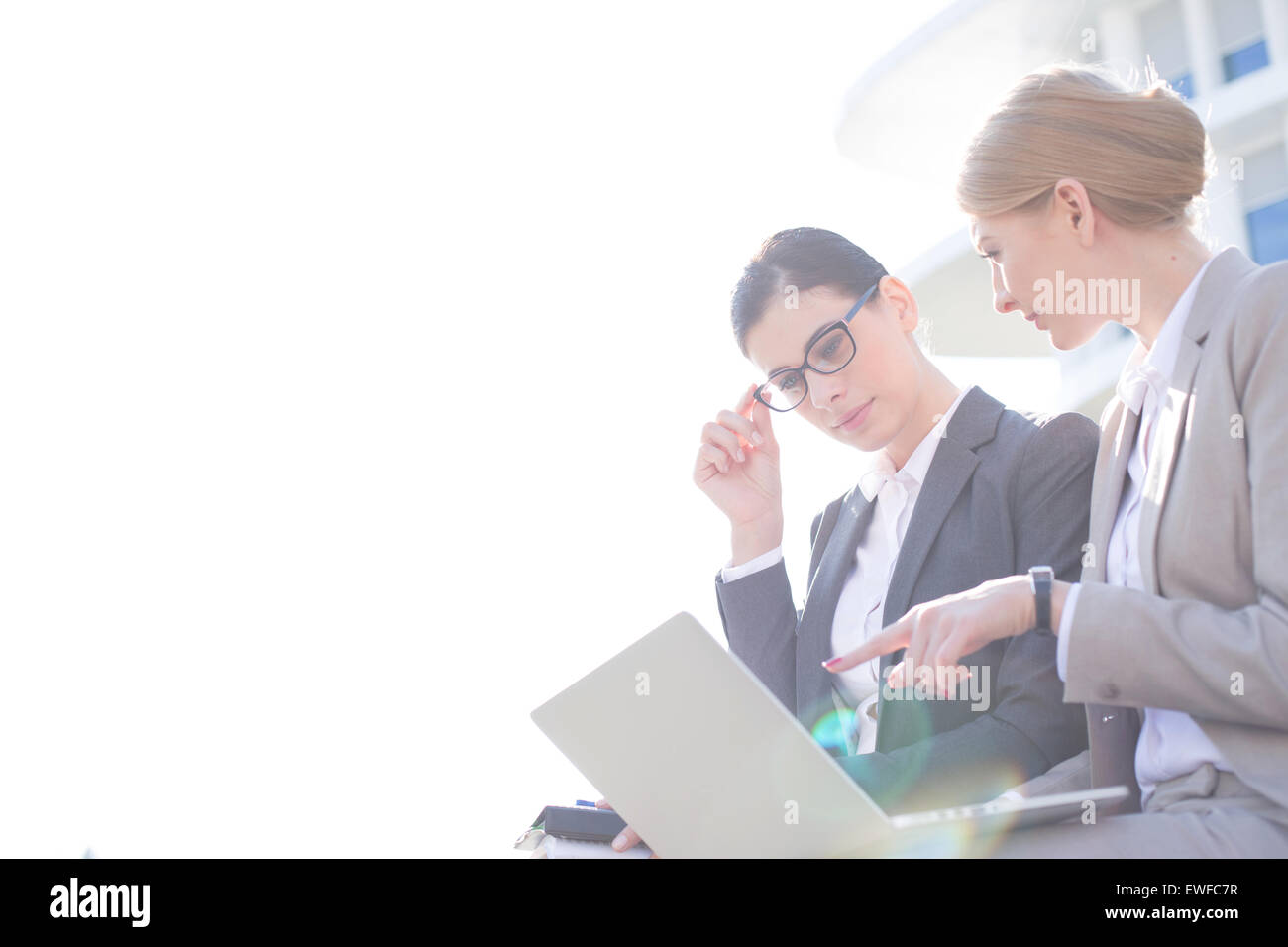 Low angle view of businesswomen using laptop contre ciel clair Banque D'Images