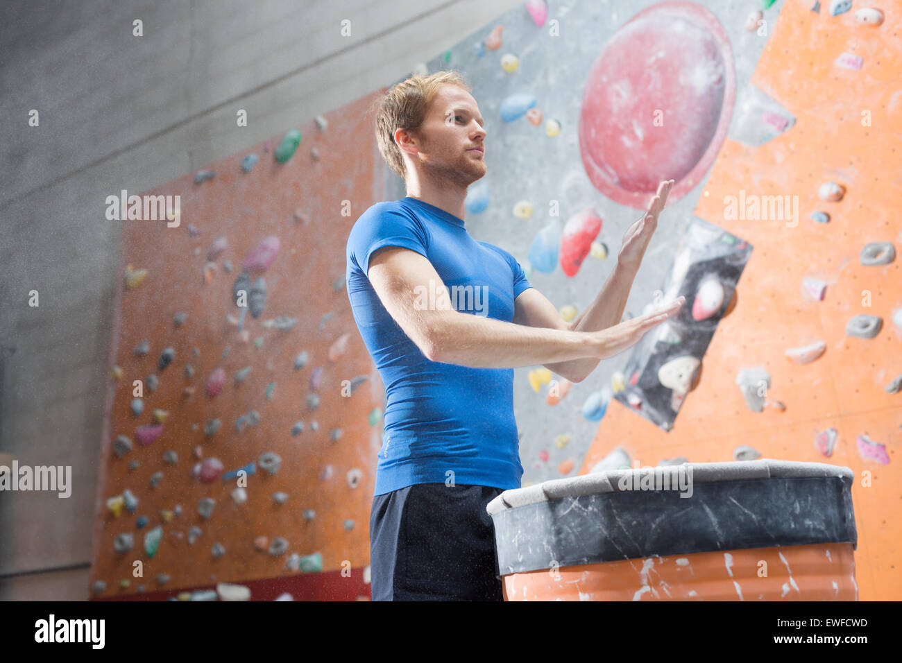 Low angle view of man dusting poudre en mur d'escalade en salle de sport crossfit Banque D'Images