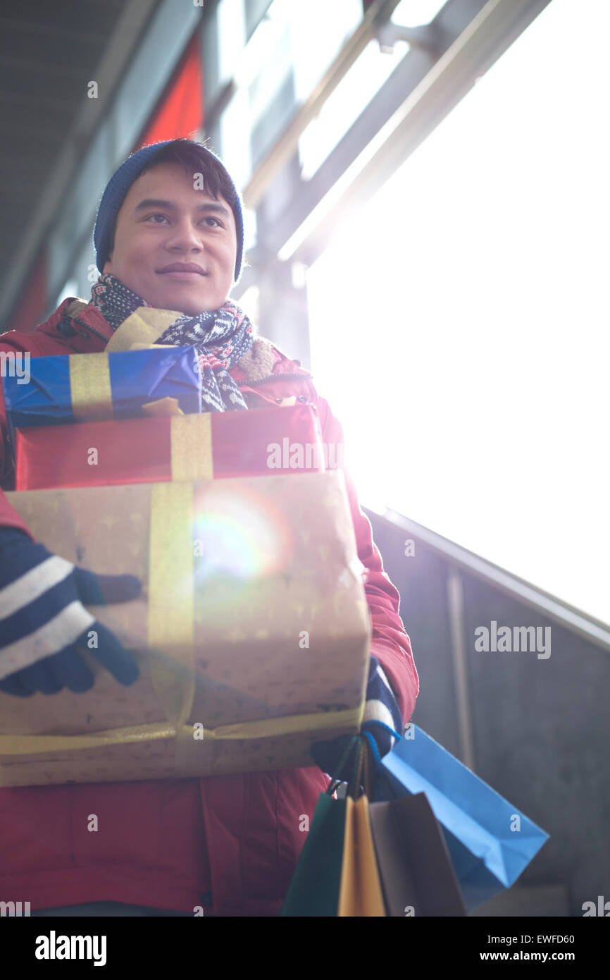 Low angle view of man holding gifts by window Banque D'Images