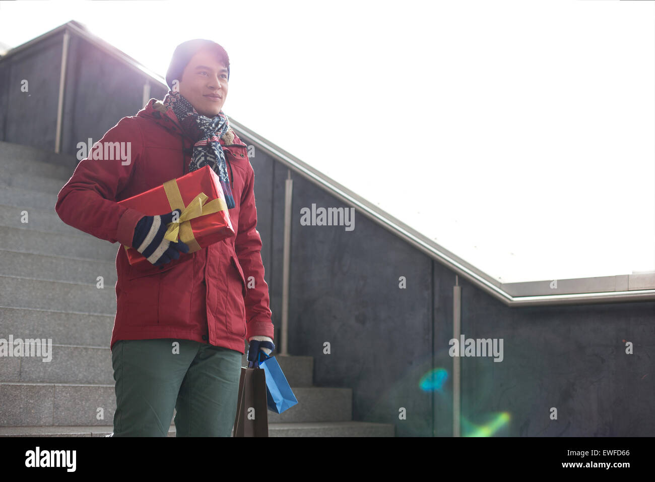 Smiling man holding gifts tout en se déplaçant vers le bas comme suit Banque D'Images