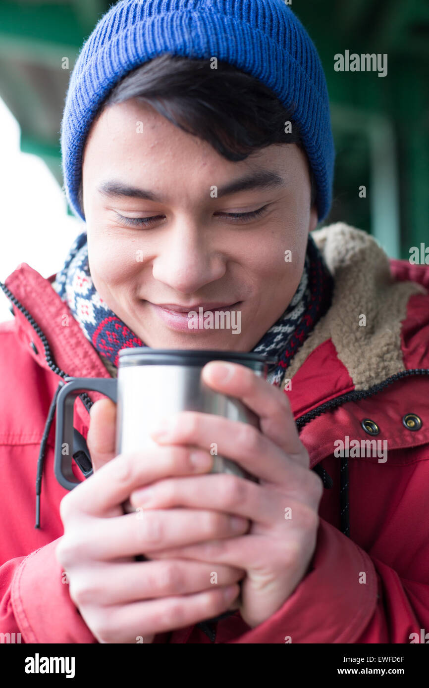 Smiling man looking at café en verre isolé conteneur lors de l'hiver Banque D'Images