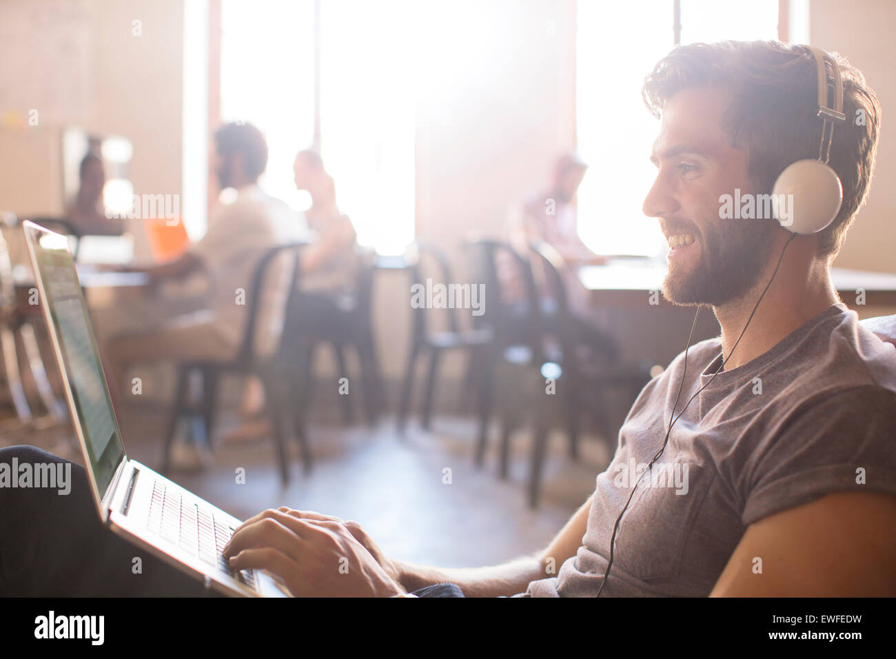Businessman wearing headphones et working at laptop in office Banque D'Images