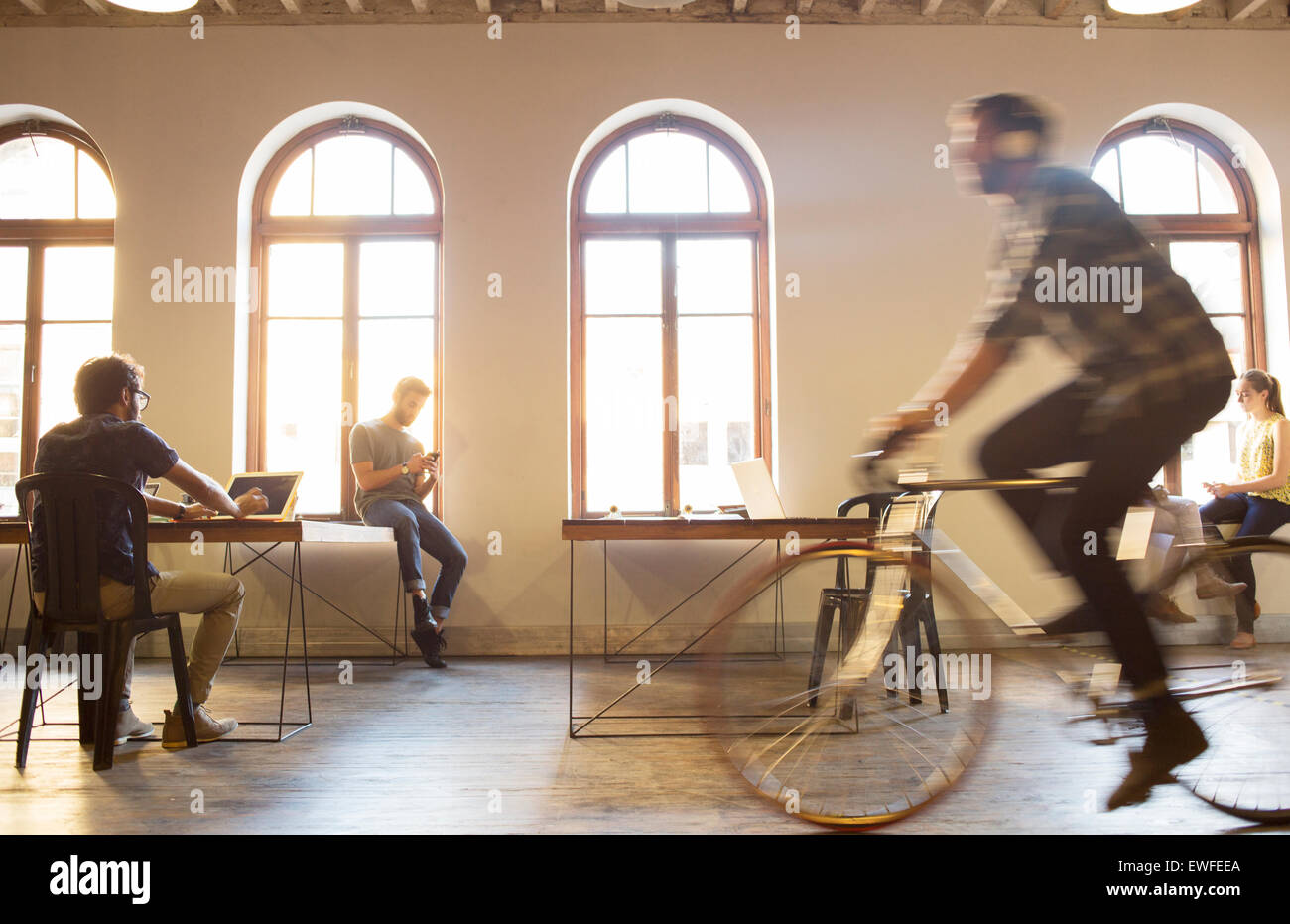 Businessman riding bicycle in open office Banque D'Images