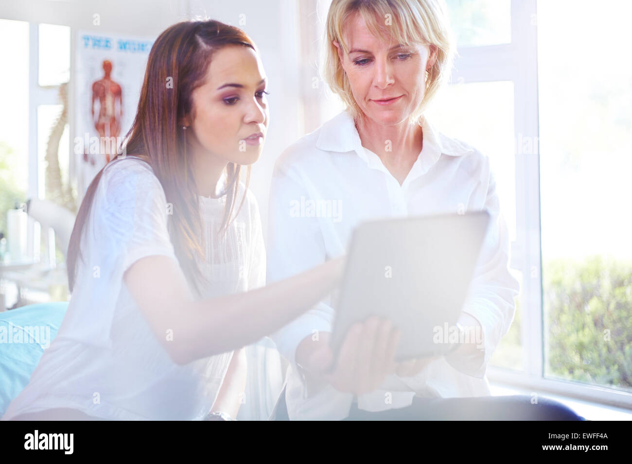 Thérapeute physique et patient using digital tablet in examination room Banque D'Images