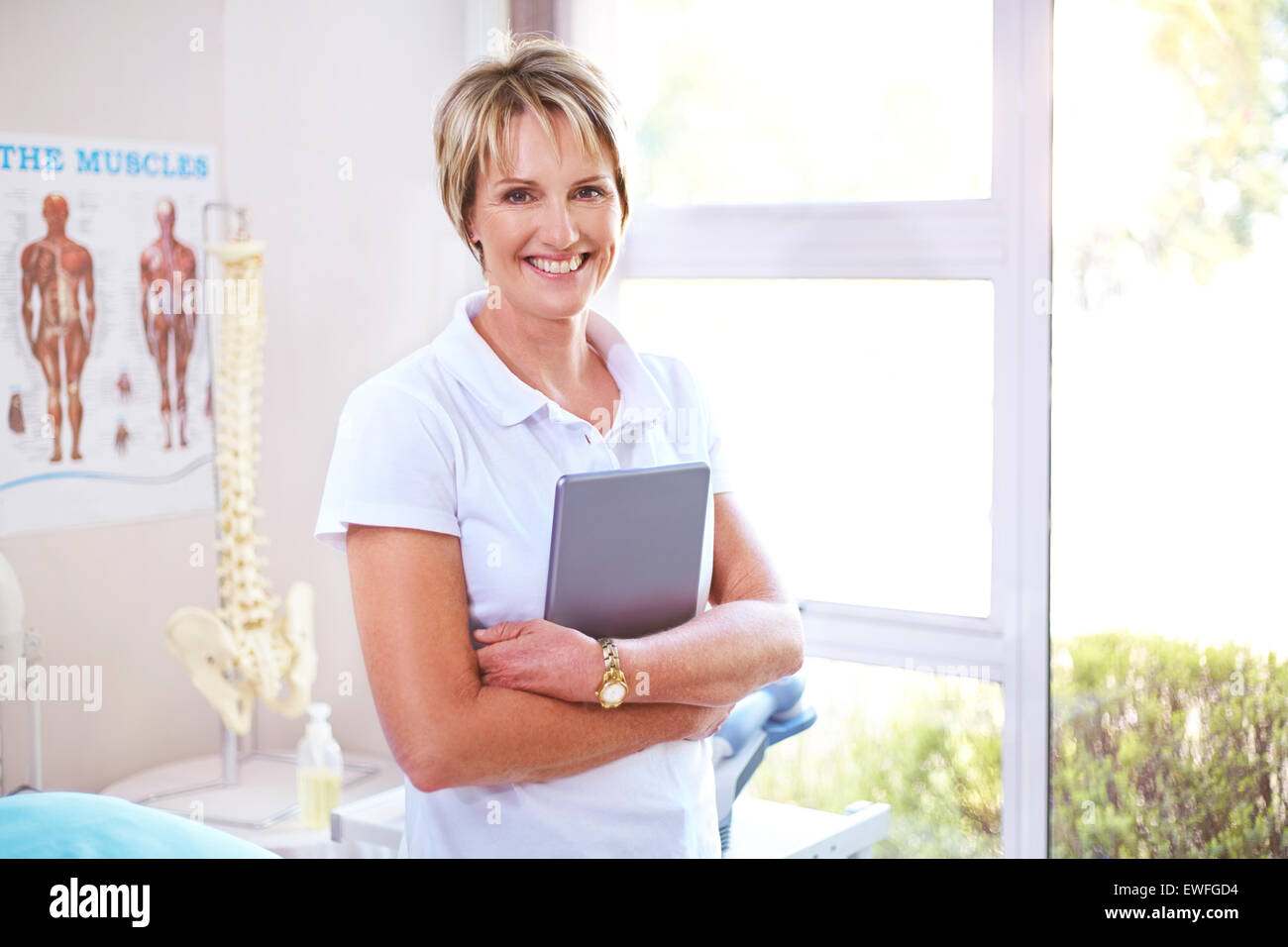 Portrait confiant physiothérapeute with digital tablet in examination room Banque D'Images