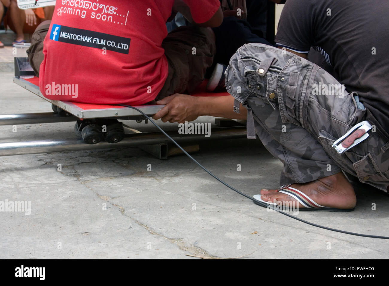 Un homme est le roulement d'un dolly sur les voies tout en travaillant dans le cadre d'une équipe de tournage à Phnom Penh, Cambodge. Banque D'Images