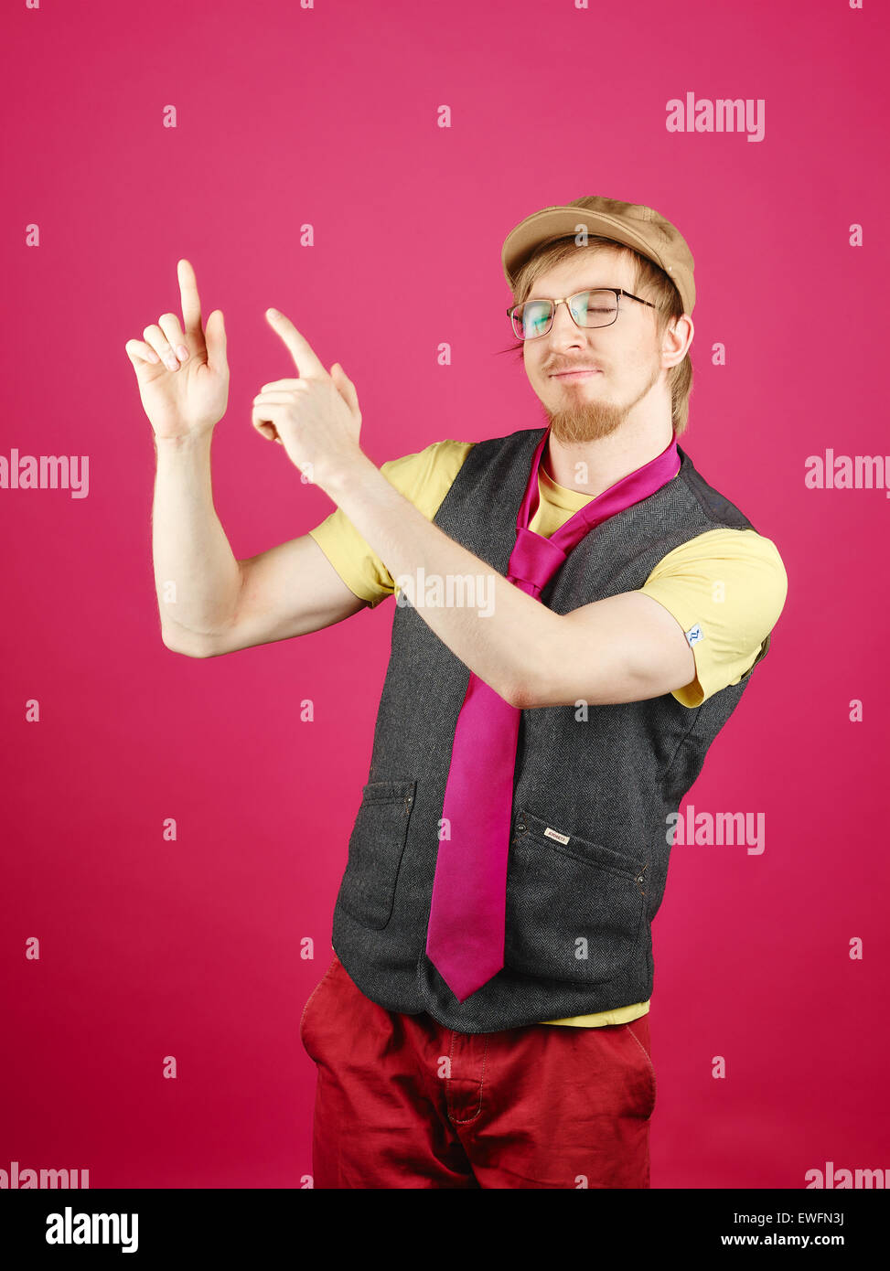 Hipster expressif portant une veste et cravate rose, fond rose et studio shot Banque D'Images