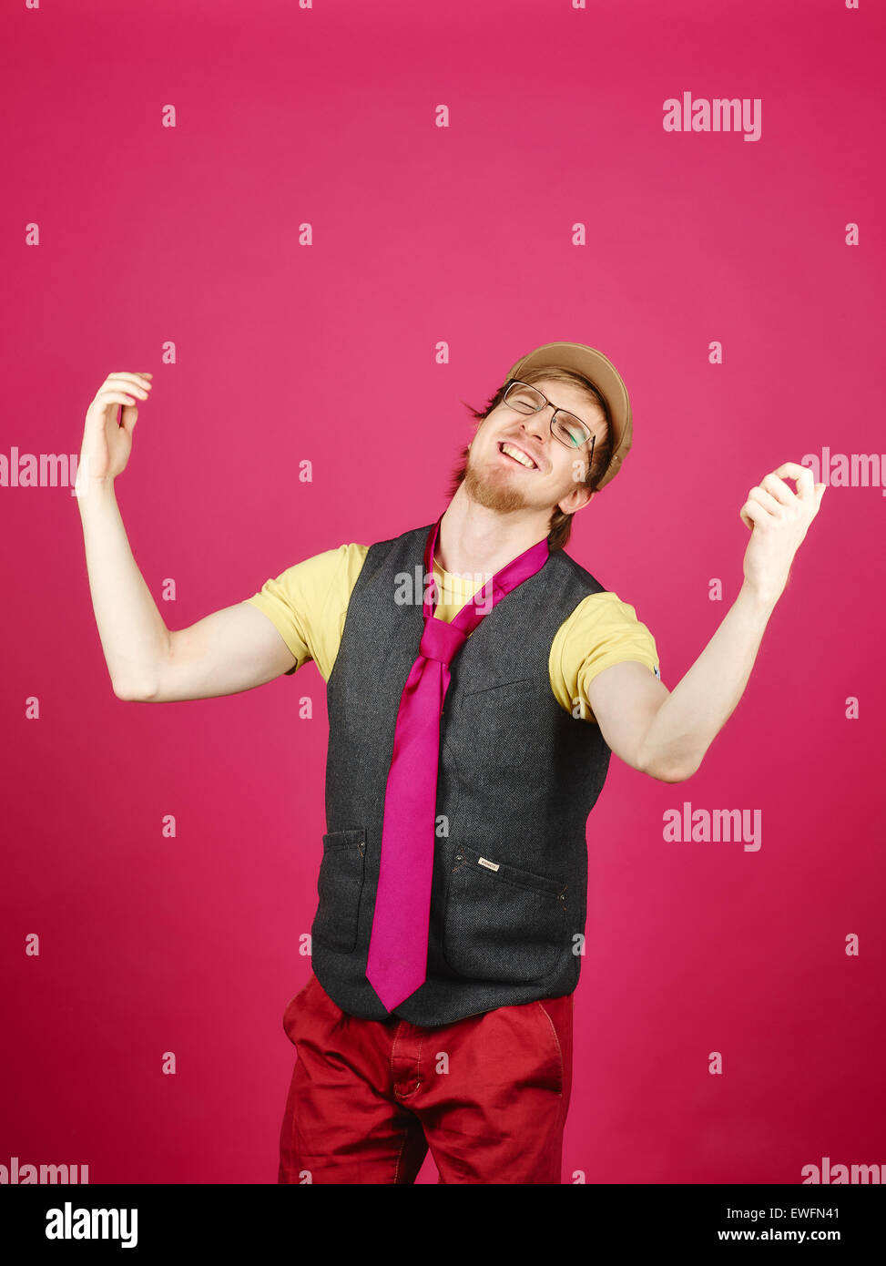Hipster expressif portant une veste et cravate rose, fond rose et studio shot Banque D'Images