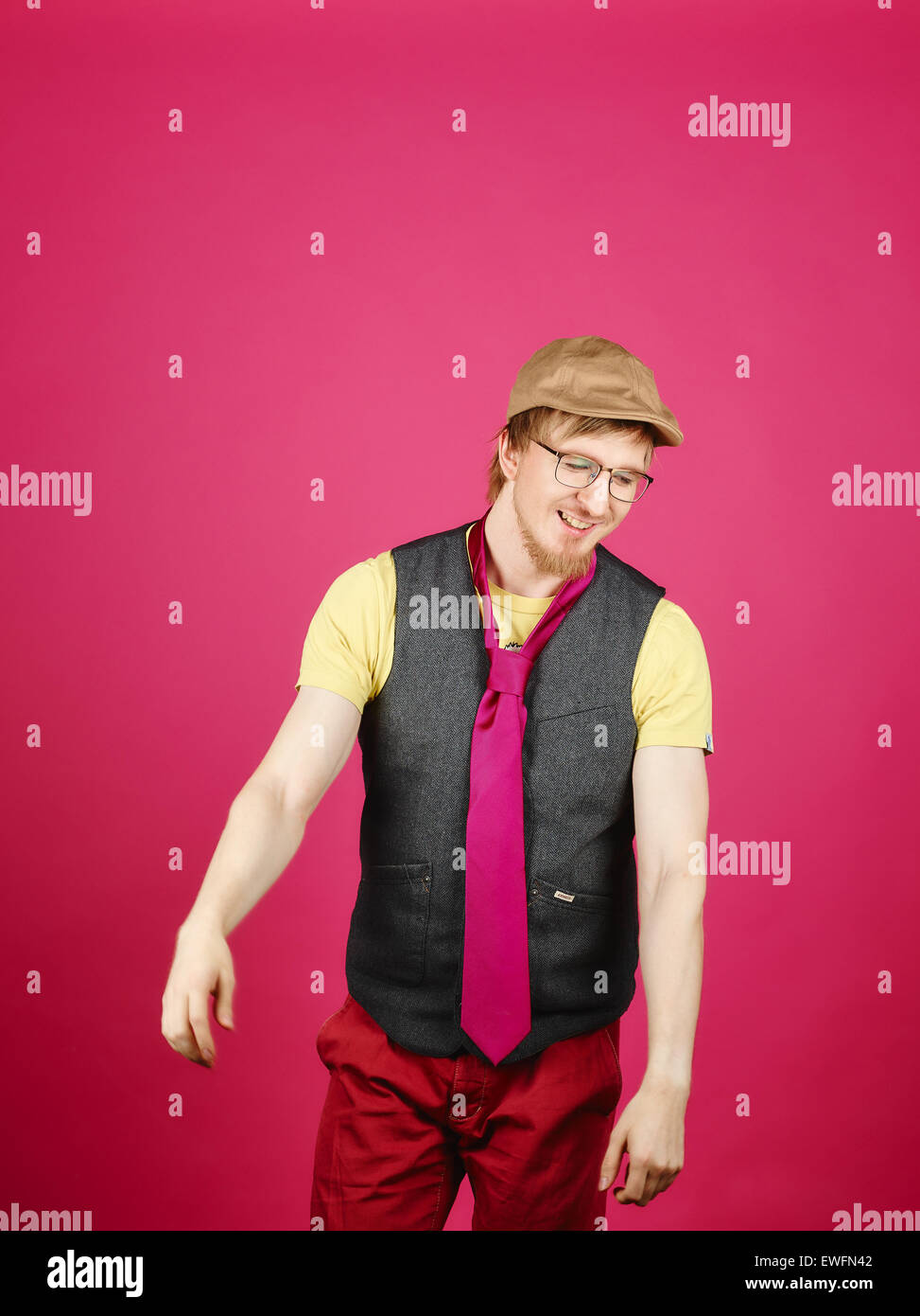 Hipster expressif portant une veste et cravate rose, fond rose et studio shot Banque D'Images