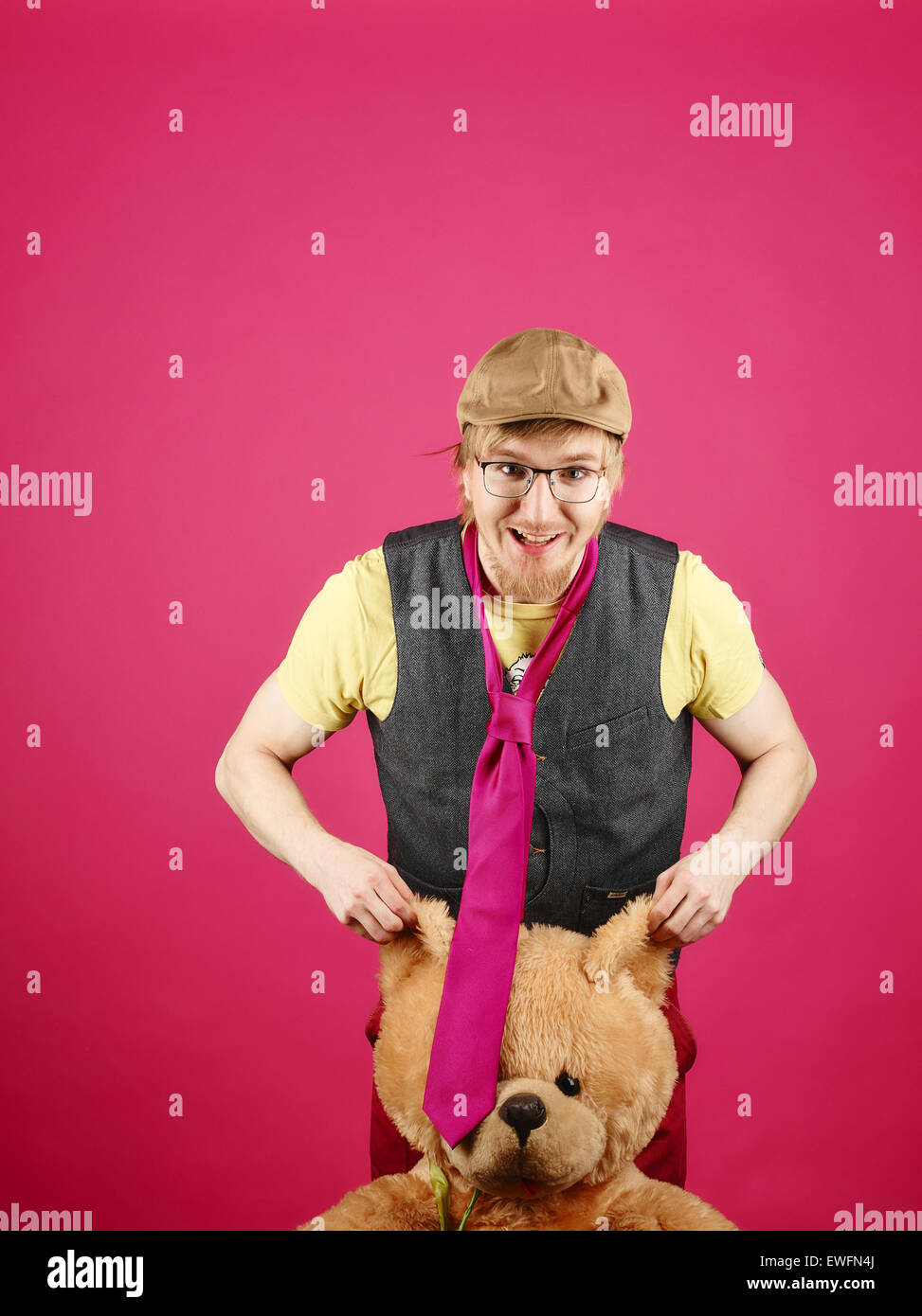 Hipster expressif portant une veste et cravate rose et il est titulaire d'ours, fond rose et studio shot Banque D'Images