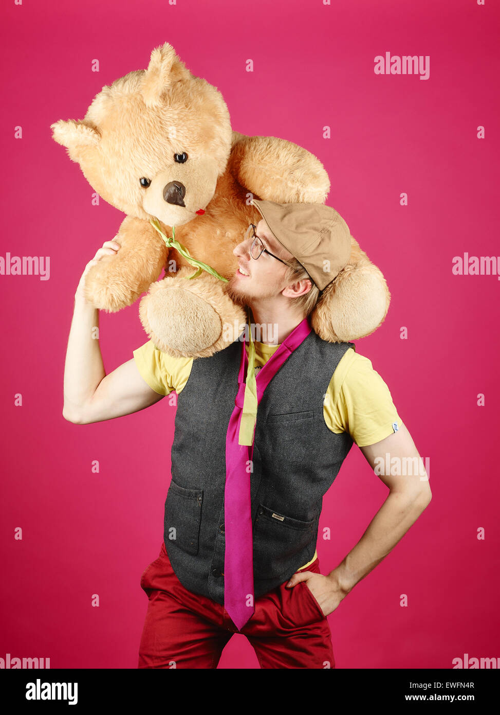 Hipster expressif portant une veste et cravate rose et il est titulaire d'ours, fond rose et studio shot Banque D'Images