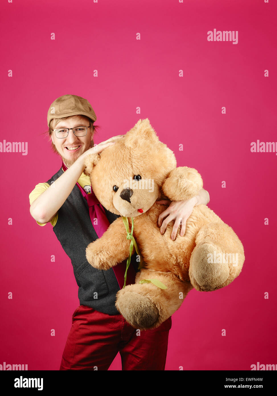 Hipster expressif portant une veste et cravate rose et il est titulaire d'ours, fond rose et studio shot Banque D'Images