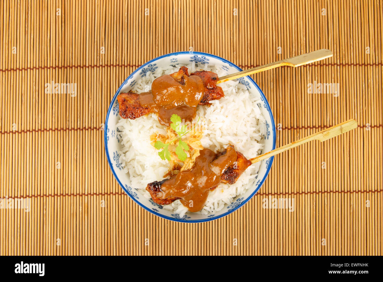 Vue de dessus d'un bol de riz avec deux brochettes de porc grillées et sauce satay Banque D'Images