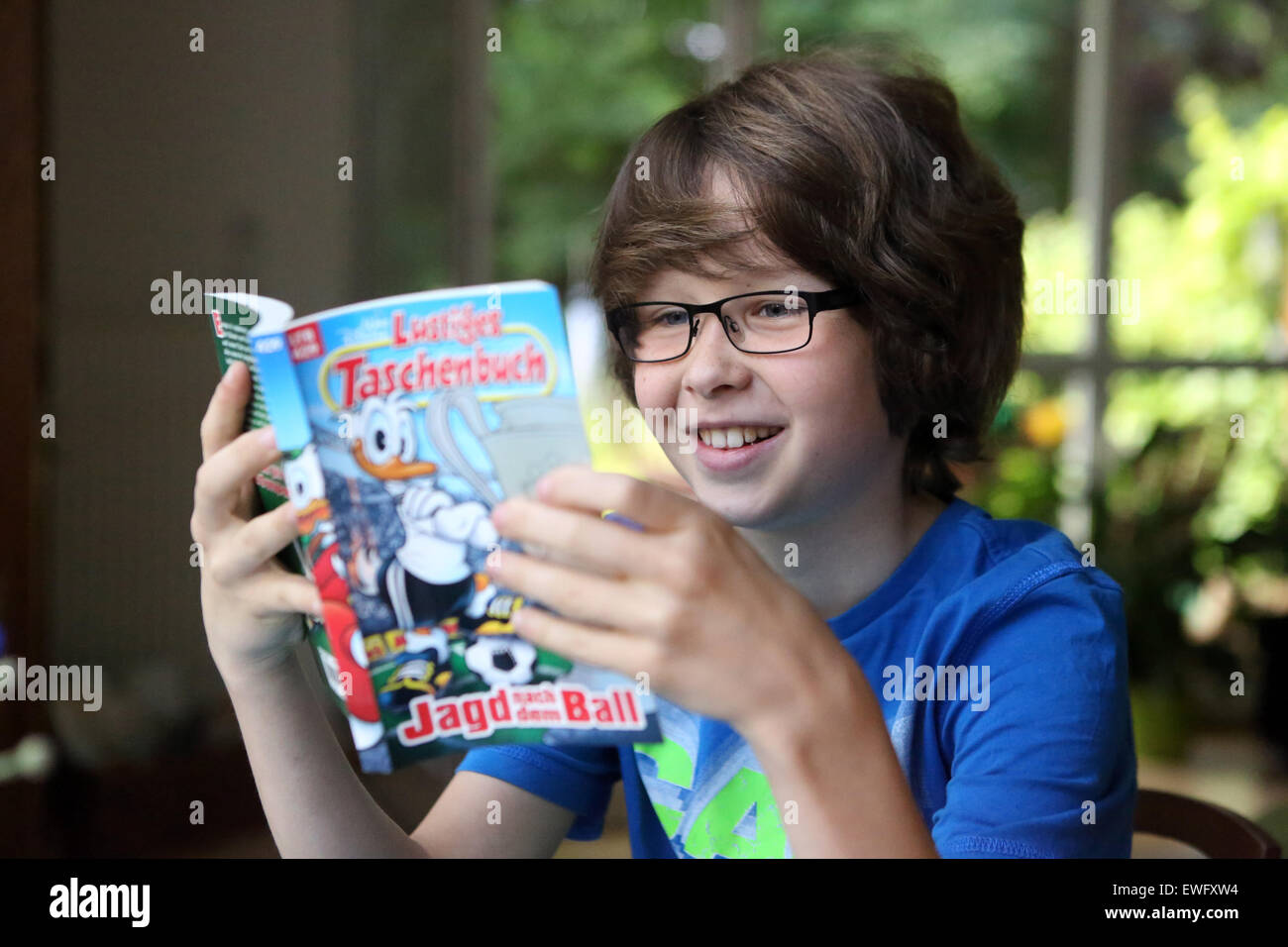Berlin, Allemagne, le Garçon à lunettes lecture une bande dessinée Banque D'Images