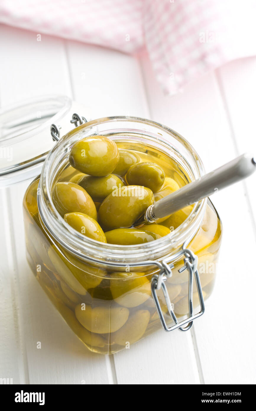 Olives vertes confites en pot sur la table de cuisine Banque D'Images