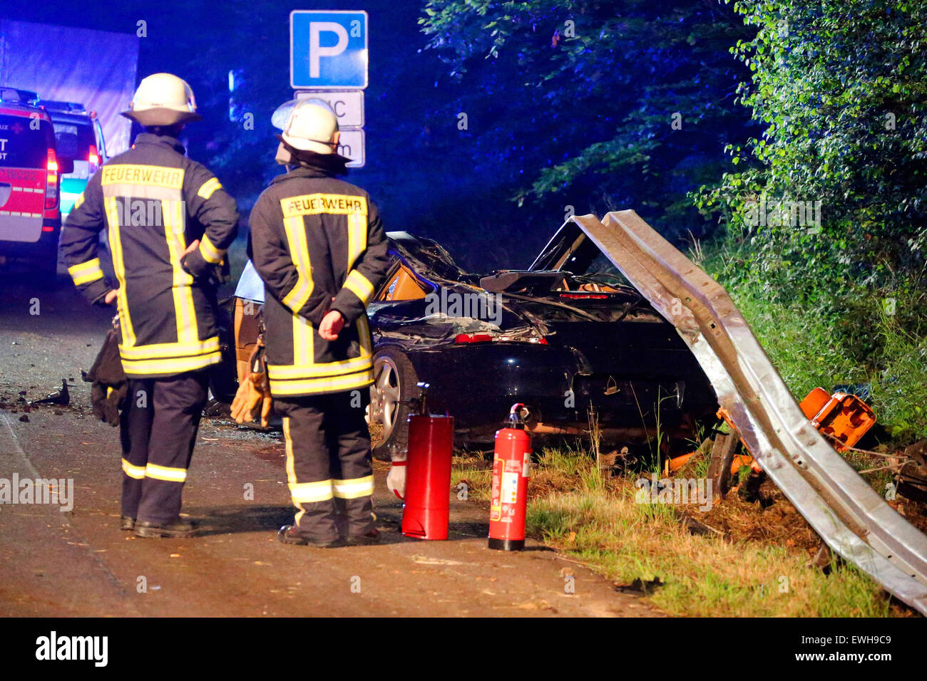 Saint Ingbert, Allemagne. 26 Juin, 2015. Les pompiers se tenir à côté d'une Porsche a complètement démoli à la suite d'un accident de voiture sur l'autoroute A6 près de St Ingbert, Allemagne, 26 juin 2015. Un bébé et un 21-year-old femme ont été tués dans l'accident. Le jeune homme de 26 ans et deux petits enfants ont subi des blessures graves. Selon la police, la voiture est entrée en contact avec la barrière centrale avant de s'écraser dans le marquage au sol adverse. PHOTO : Becker&Bredel/dpa/Alamy Live News Banque D'Images
