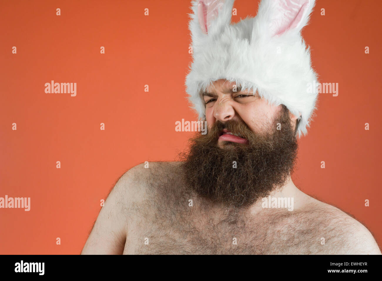 Gros homme barbu dégoûté porte des oreilles de lapin stupide Banque D'Images