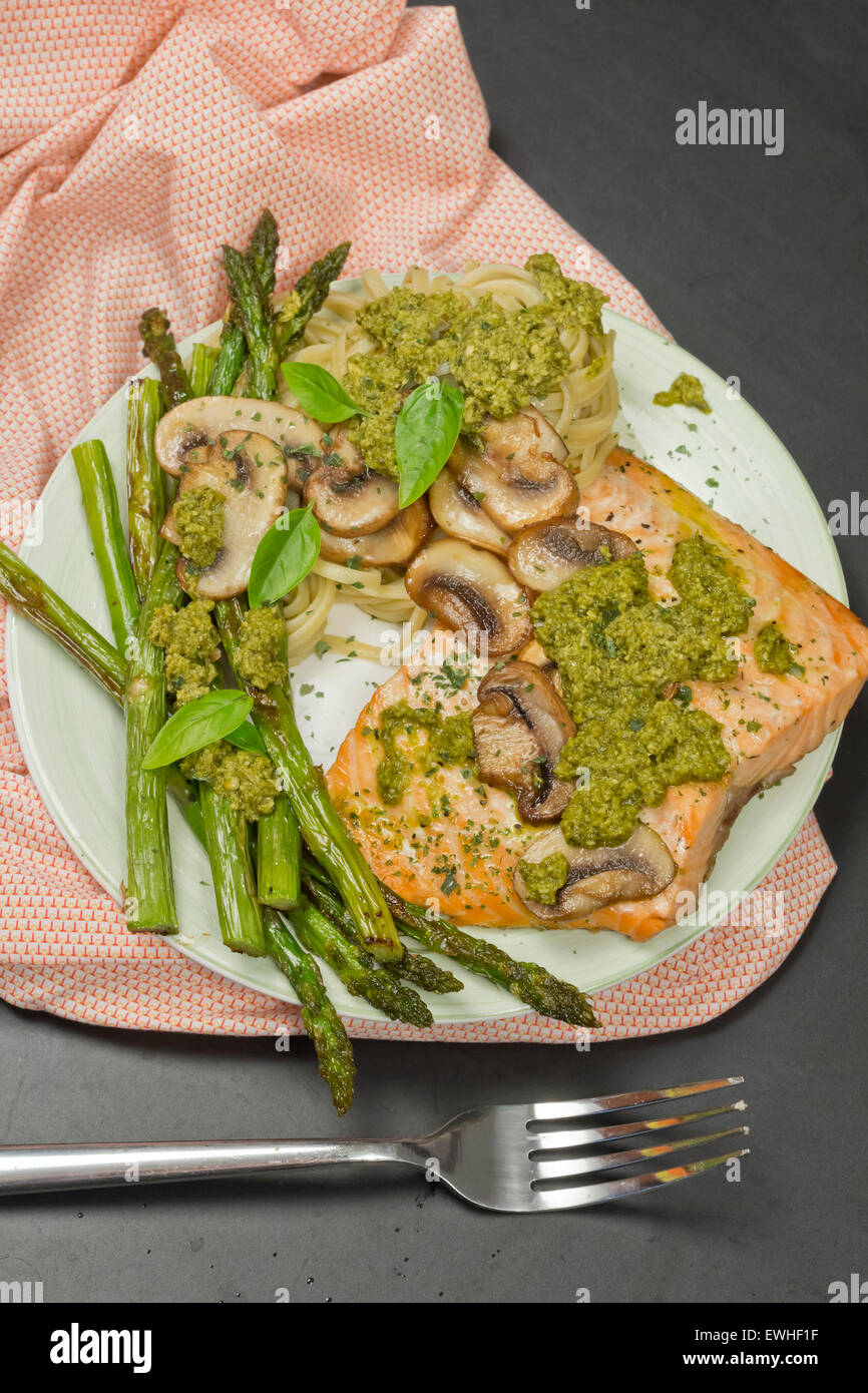 Délicieux saumon grillé avec sauce crémeuse au pesto, asperges et linguine sur le côté Banque D'Images