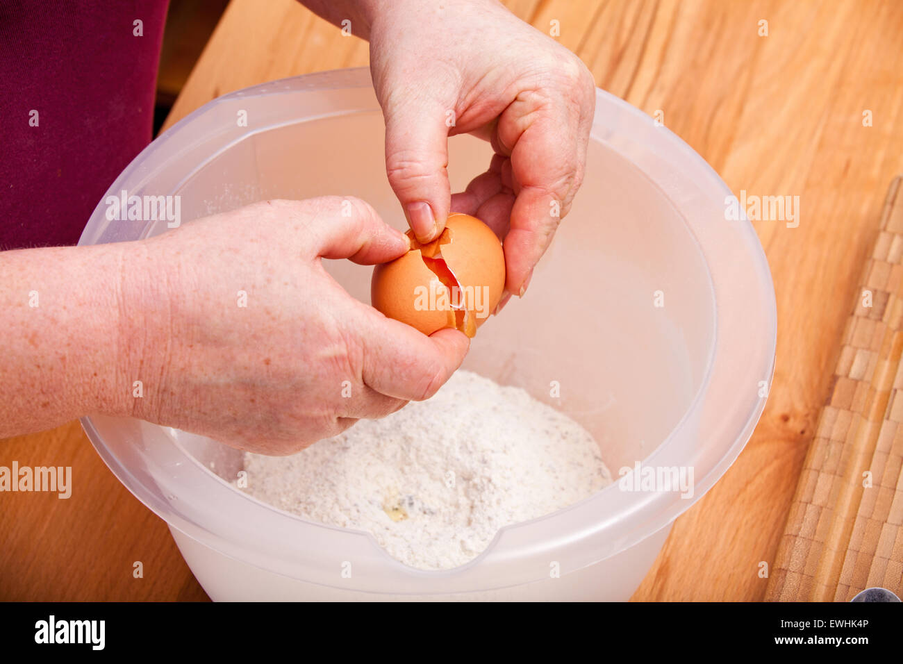 Pour casser un oeuf dans le bol avec la pâte à gâteau Banque D'Images
