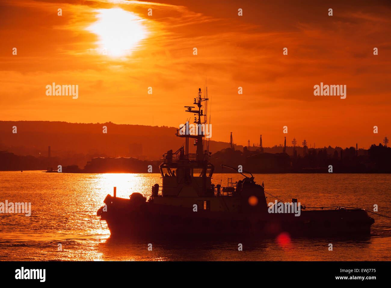Au coucher du soleil de la mer Noire. Navire remorqueur est en cours, le port de Varna, Bulgarie. Photo avec effet lens flare naturel Banque D'Images