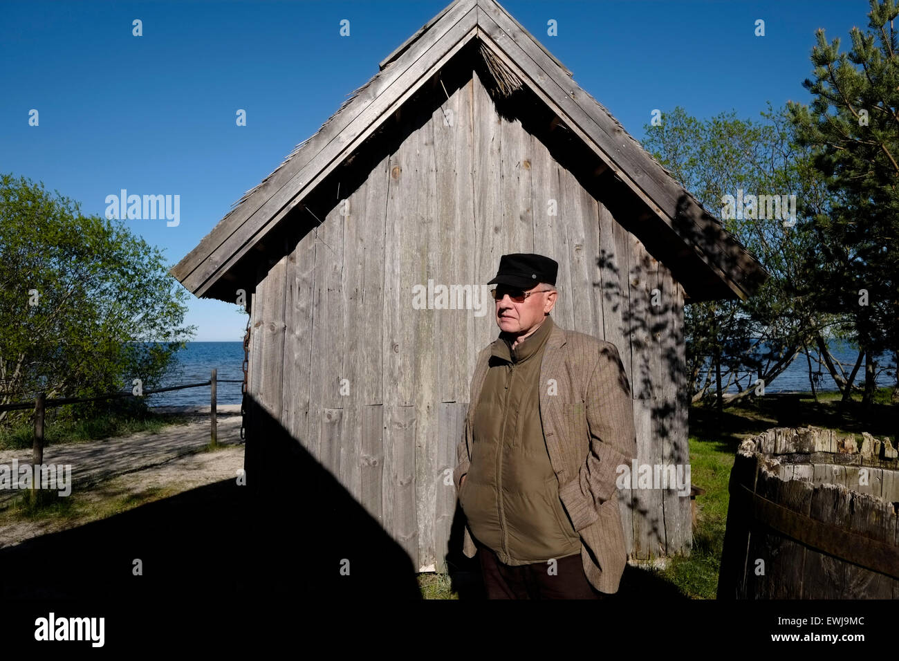 Un ancien pêcheur letton se place en avant d'une authentique maison de pêcheurs à Ragakapa Open Air Museum qui dépeint la vie quotidienne des pêcheurs au début du 20e siècle situé au pied de la dune "Ragakapa" près de Jurmala Lettonie une ville balnéaire sur le golfe de Riga à la côte de la mer Baltique, République de Lettonie Banque D'Images