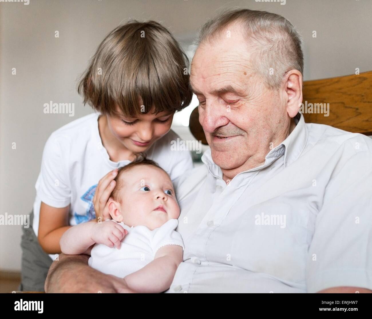 Grand-père tenant une naissance d'un bébé fille à côté de son petit-fils  d'âge scolaire Photo Stock - Alamy