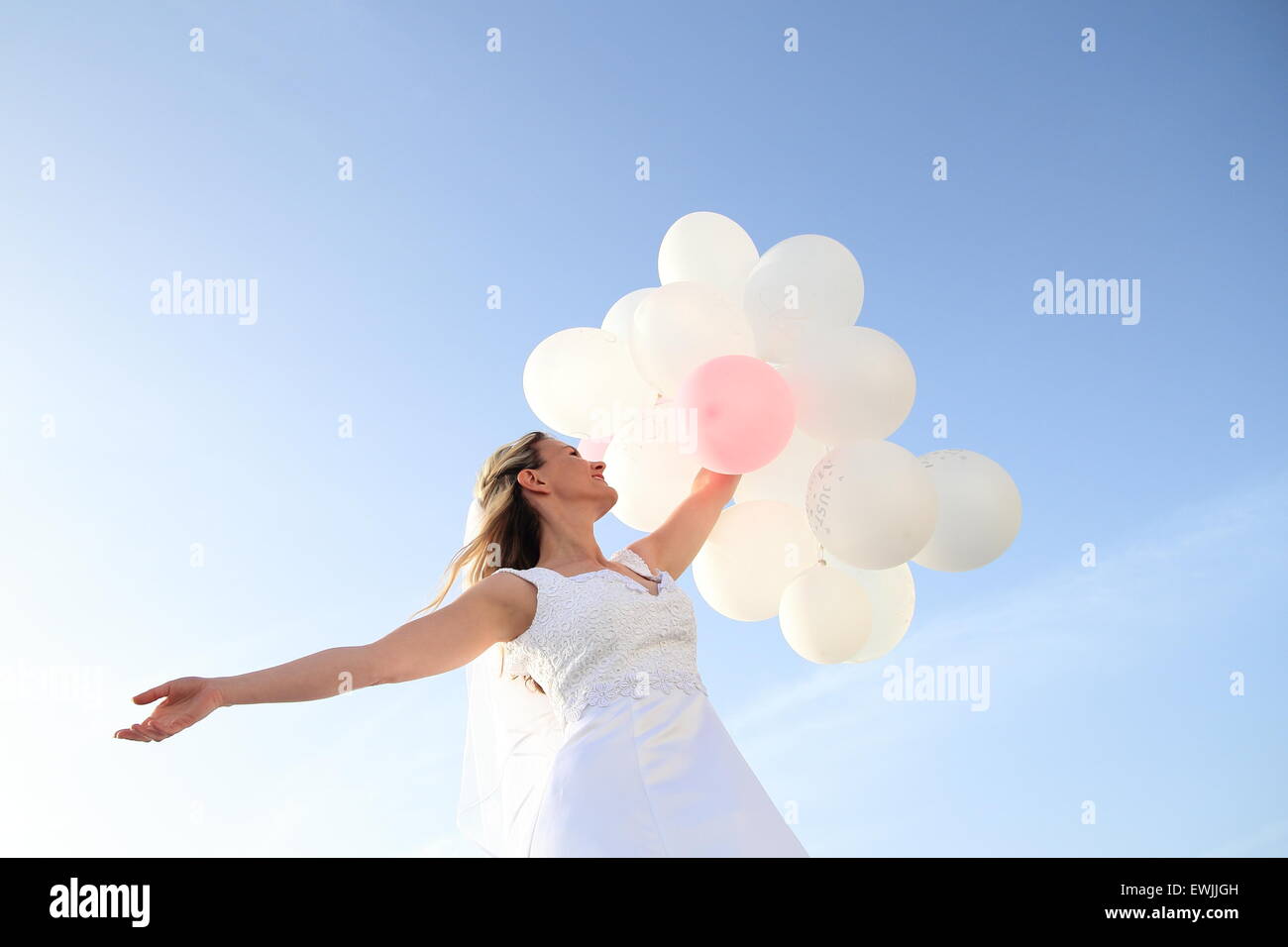 Une heureuse mariée avec des ballons blancs dans le ciel bleu Banque D'Images