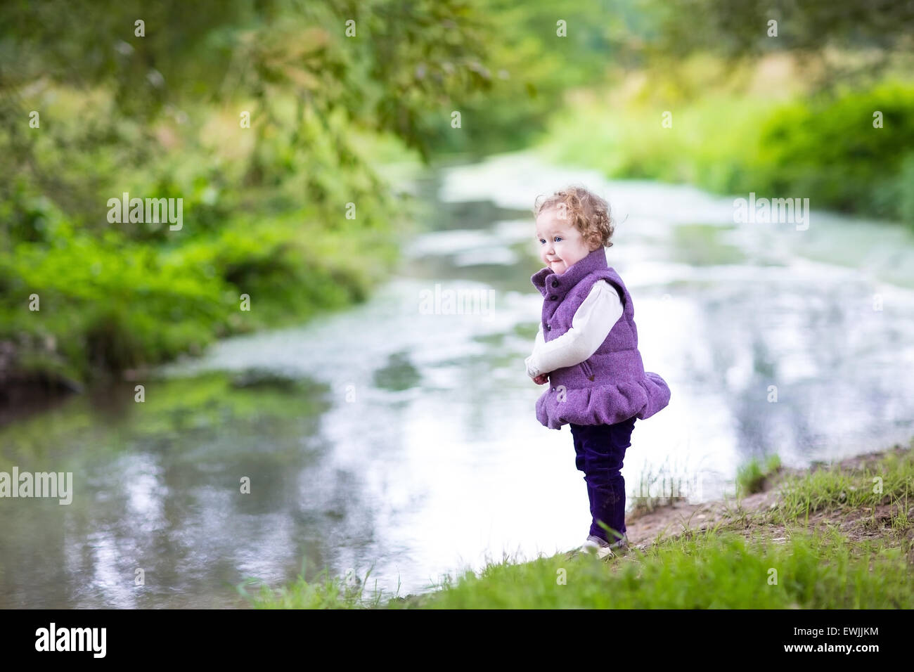 Belle petite fille marche sur une rive de la rivière sur une belle journée d'automne Banque D'Images