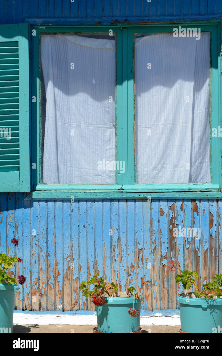 Un cadre de fenêtre peint en vert et bleu haletait mur en bois dans le village de Loutro, Crète, Grèce Banque D'Images