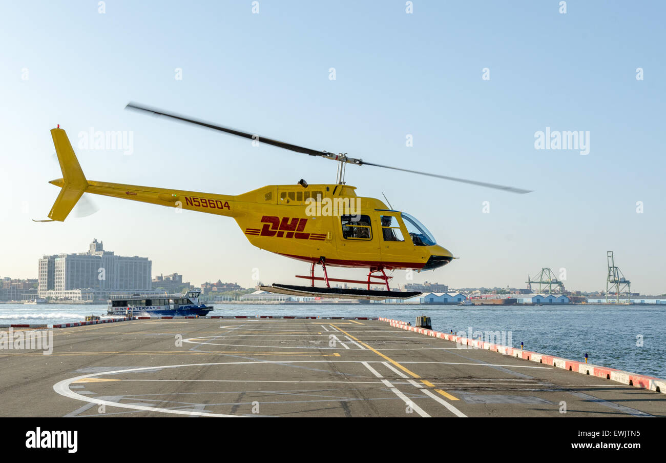 En hélicoptère Bell 206 couleurs DHL décollant de l'héliport de Wall Street à Manhattan, New York Banque D'Images