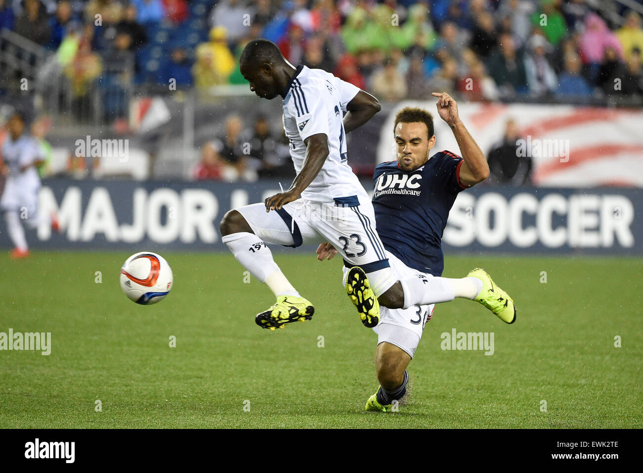 Foxborough, Massachusetts, USA. 27 Juin, 2015. Avant FC Vancouver Kekuta Manneh (23) voyages pendant New England Revolution defender Kevin Alston (30) tout en jouant la balle au cours de la MLS match entre les Whitecaps de Vancouver et le New England Revolution tenue au Stade Gillette à Foxborough dans le Massachusetts. Vancouver a battu 2-1 la Nouvelle Angleterre. Eric Canha/CSM/Alamy Live News Banque D'Images