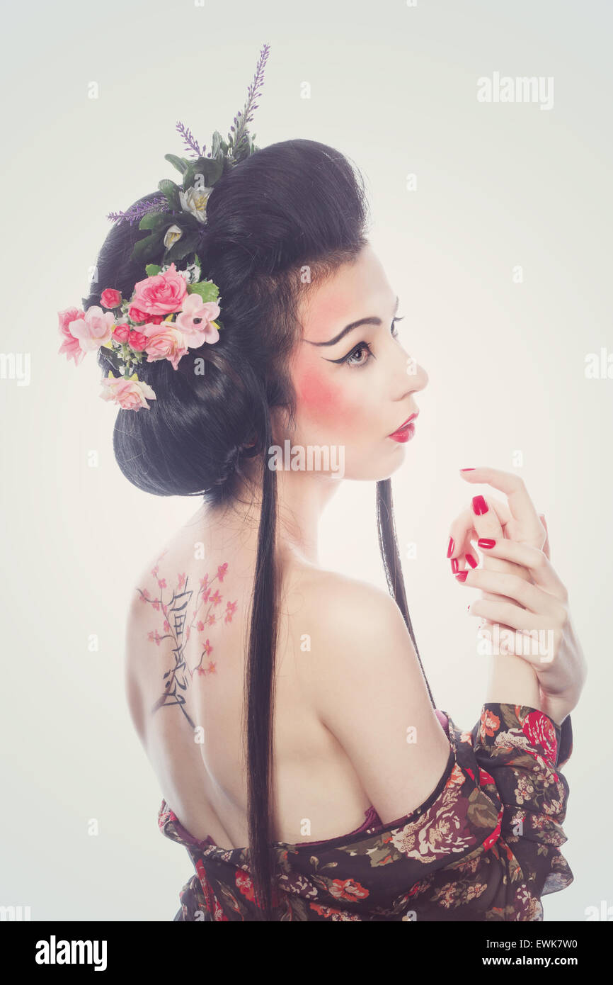Jolie jeune fille geisha. Dessin de cerise et de hiéroglyphes sur l'arrière. Le concept de beauté asiatique. Banque D'Images