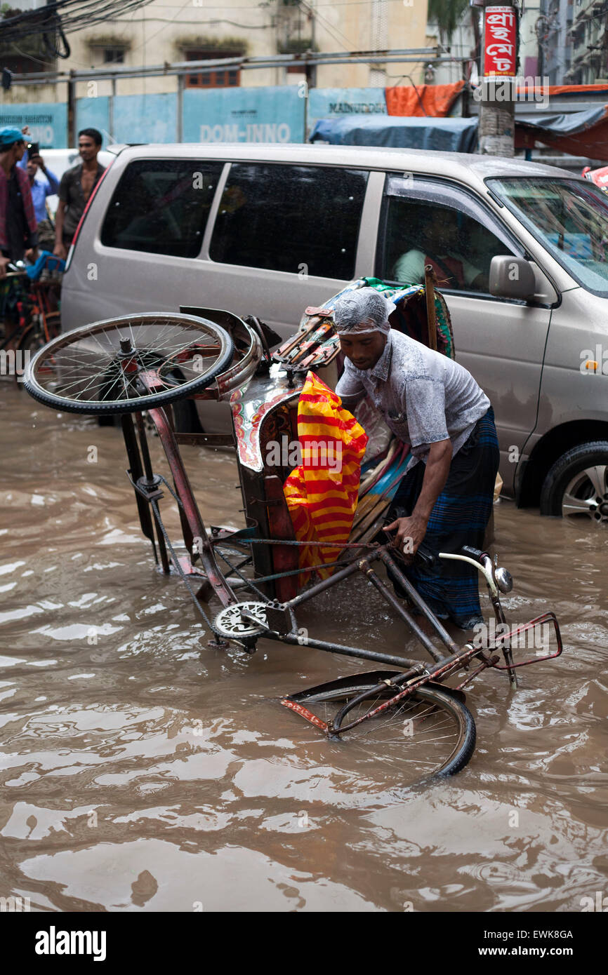 Dhaka, Bangladesh. 27 Juin, 2015. Les passagers et l'extracteur de pousse-pousse de la difficulté de sortir d'un rickshaw que débouler après une roue de il est tombé dans un trou d'eau à Dhaka le 27 juin 2015.La pluie lourde dans la ville a continué pendant quatre jours consécutifs, infligeant des souffrances sans fin sur les gens que l'eau l'exploitation forestière et les activités éducatives entravée. Zakir Hossain Chowdhury Crédit : zakir/Alamy Live News Banque D'Images