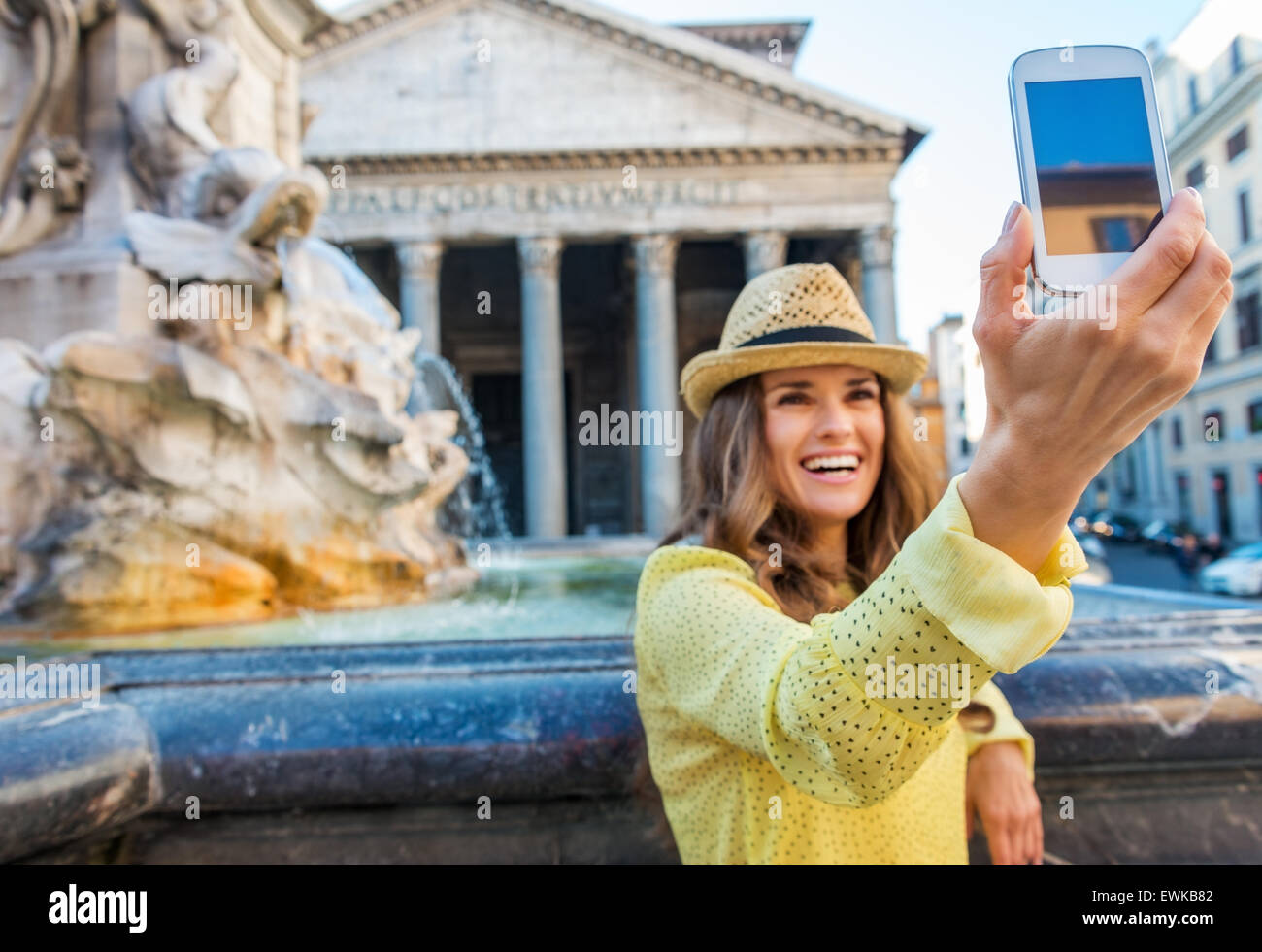Une happy brunette contient jusqu'son téléphone portable et sourit tout en prenant un Panthéon de Rome selfies avec fontaine et Panthéon behin Banque D'Images