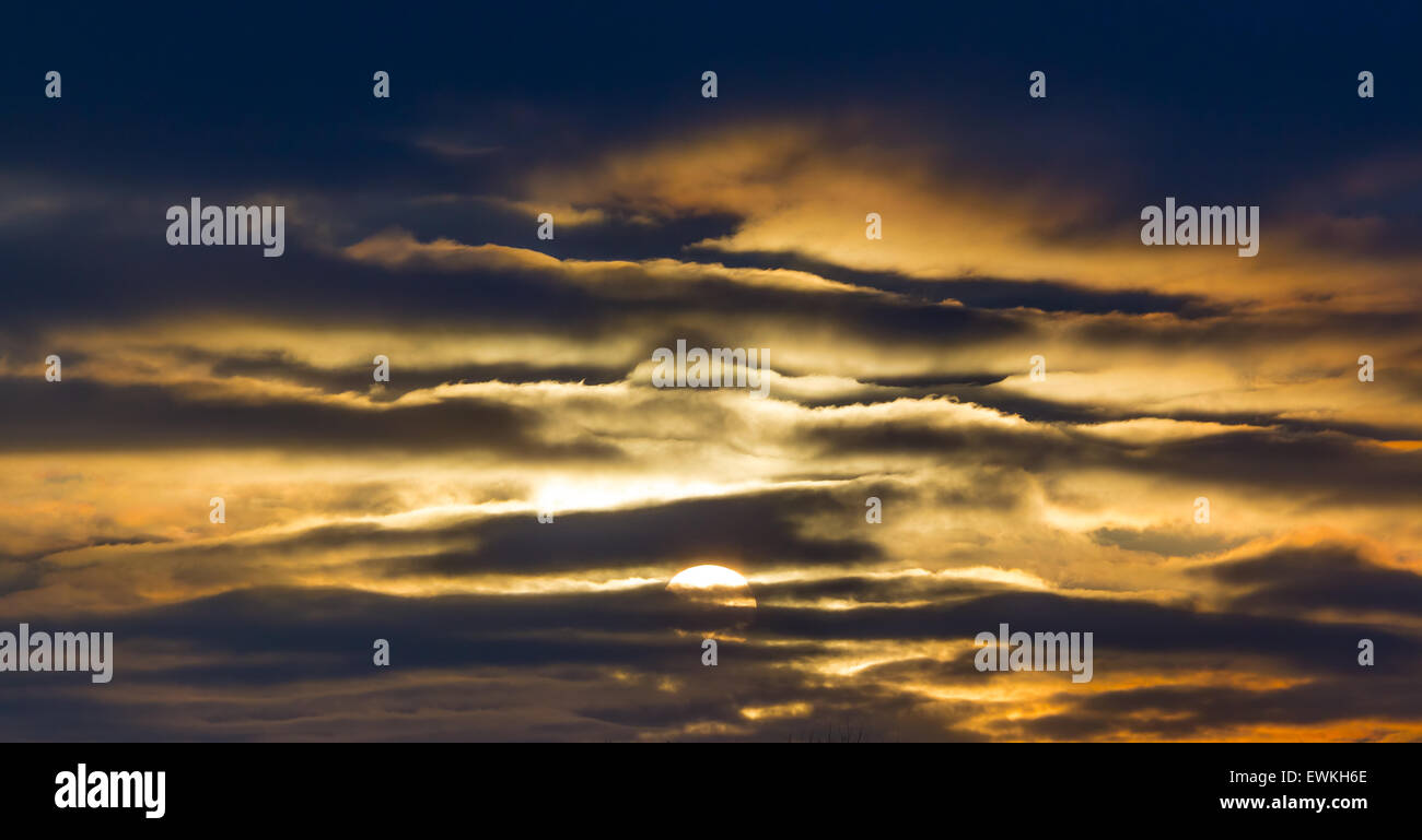 Coucher du soleil doré à travers les couches de nuages sombres Banque D'Images