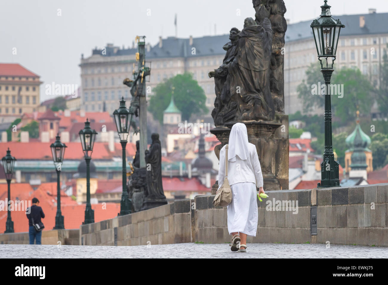 Nun de marcher seul, à l'aube d'une nonne en blanc traverse le pont Charles à Prague, République tchèque. Banque D'Images