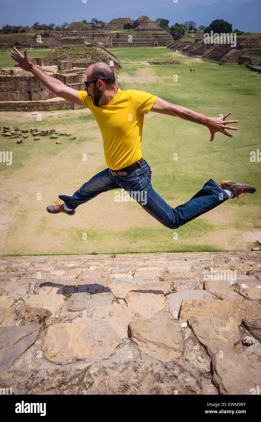 Man sautant en l'air au-dessus de l'escalier en pierre de ruines de Monte Alban au Mexique Banque D'Images