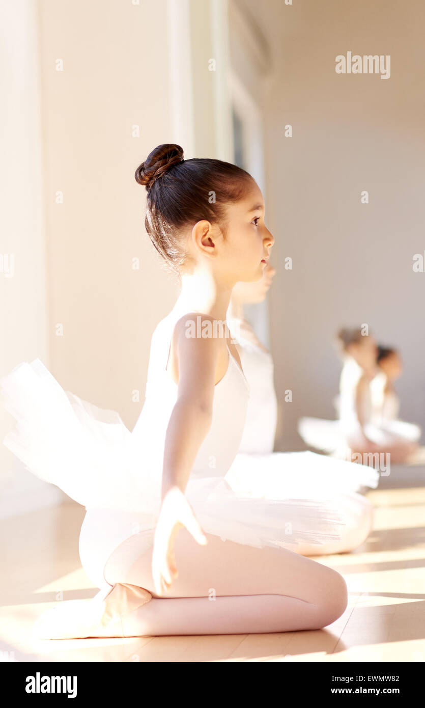 Vue latérale d'un attentif Young Pretty Ballerina Girl pendant la formation  de ballet, assis sur sa cheville avec des bras de son côté Awa Photo Stock  - Alamy