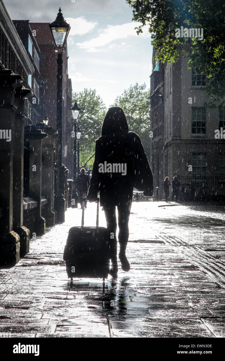 Une femme marche à travers une douche sur Queen Square à Bristol, Royaume Uni Banque D'Images