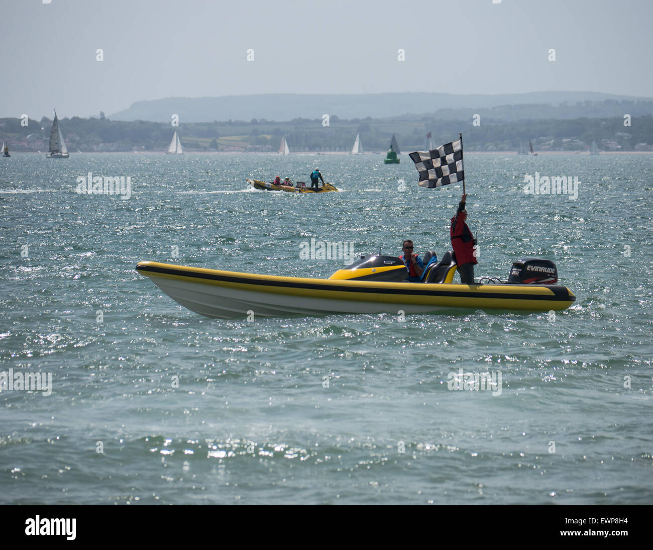Un bateau maréchaux jaune sur la ligne d'arrivée de la course de bateau d'alimentation avec un maréchal qui agitait un drapeau à damier. Banque D'Images