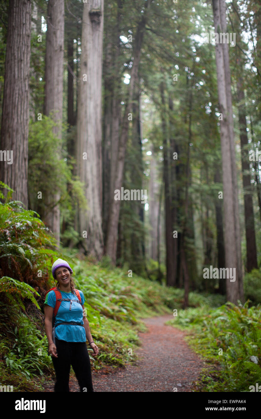 Portrait d'une femme debout sur un sentier entre les grands arbres. Banque D'Images