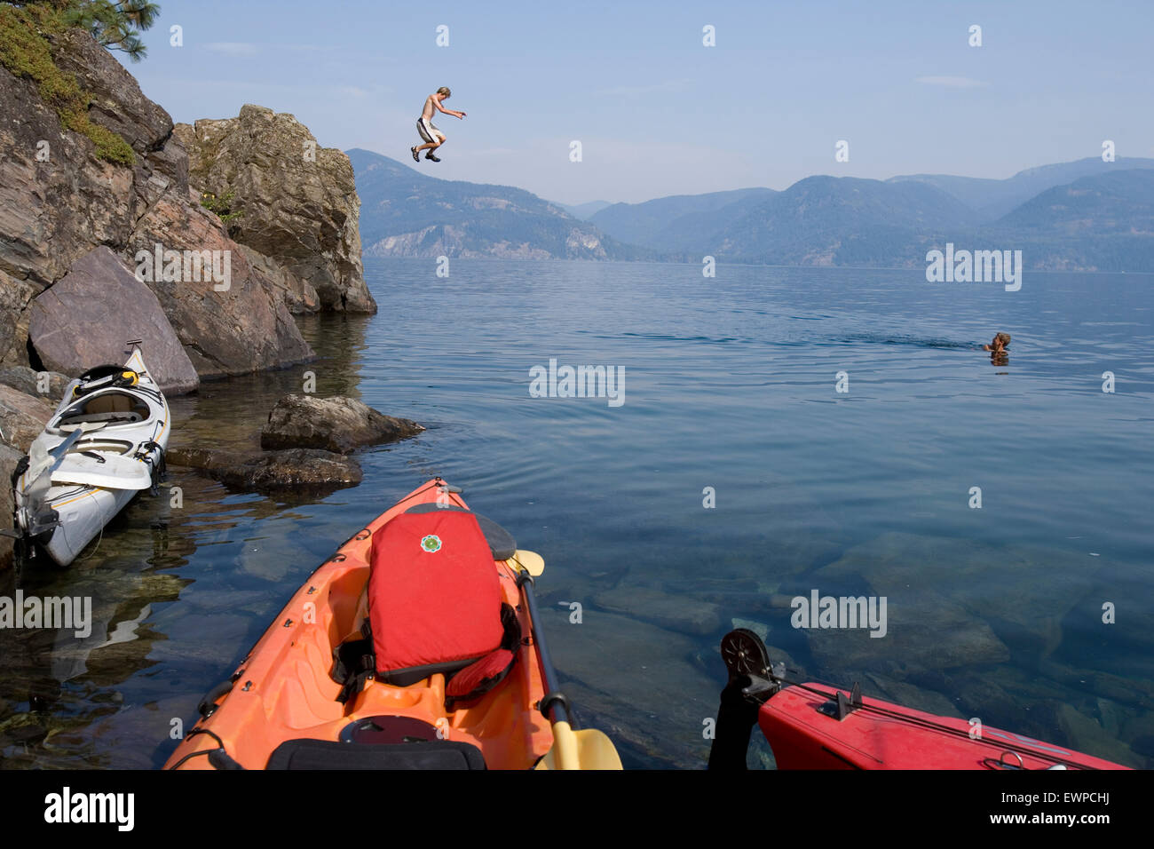 Boy Jumping off cliff dans le lac Banque D'Images