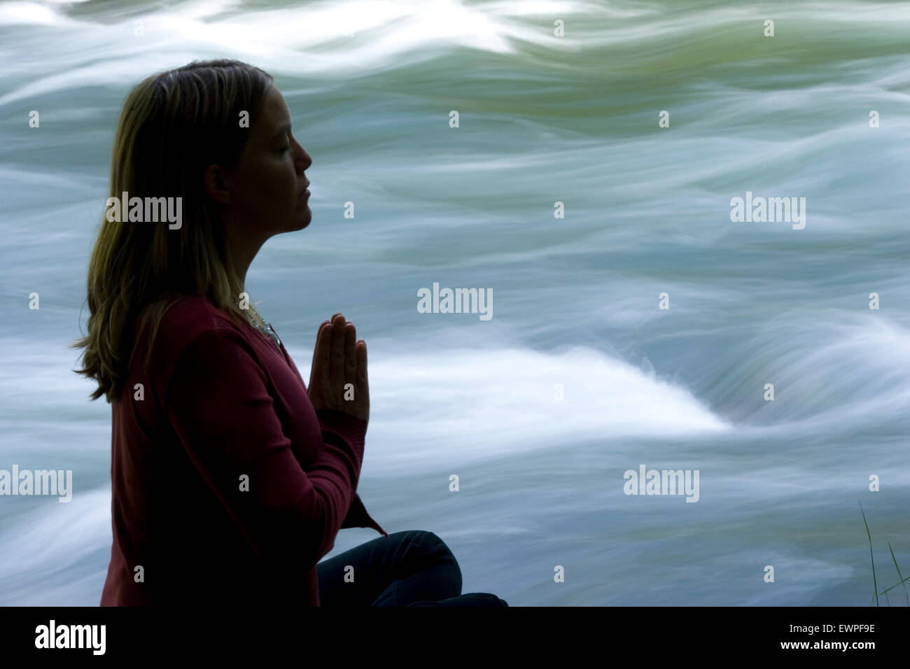 Une femme assise dans la méditation au bord d'une rivière de l'Oregon. Banque D'Images