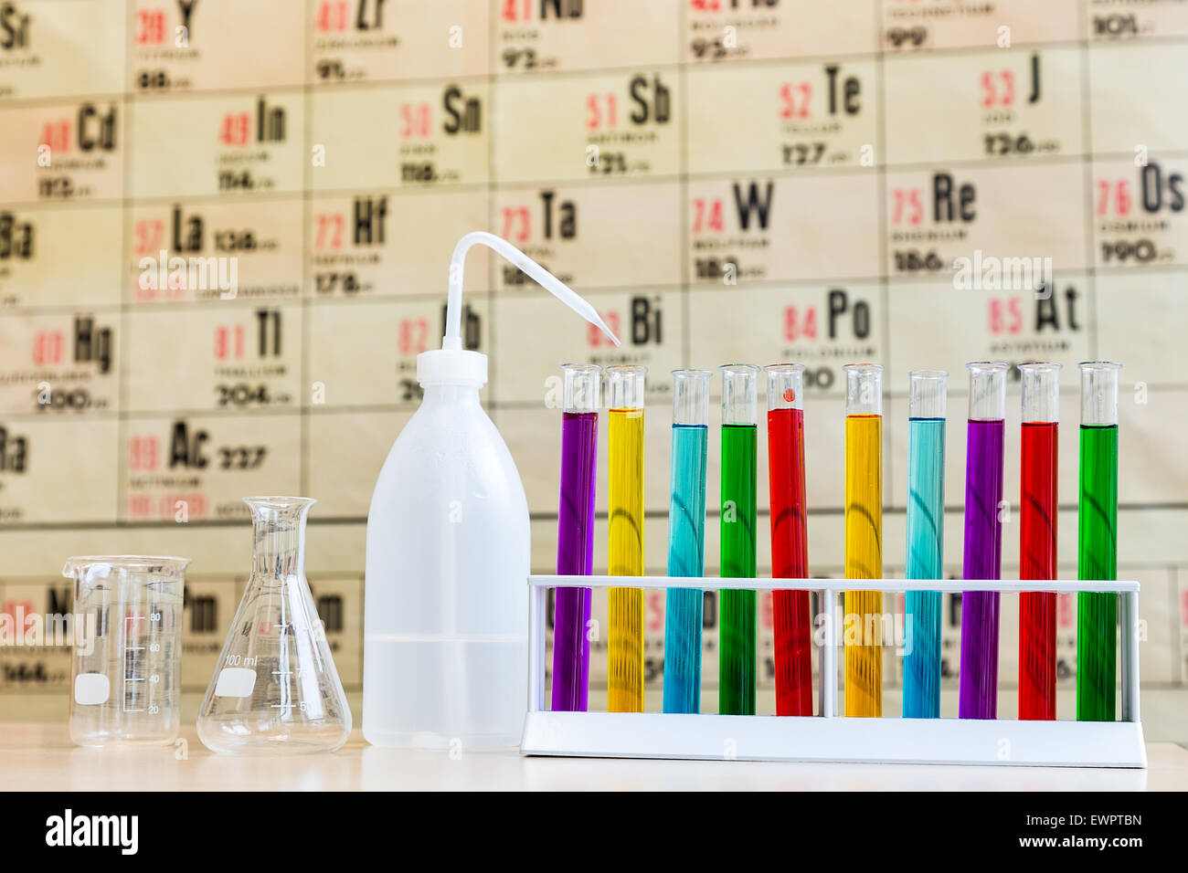 La chimie avec tubes à essai de couleur et le verre en face de carte murale montrant tableau périodique Banque D'Images