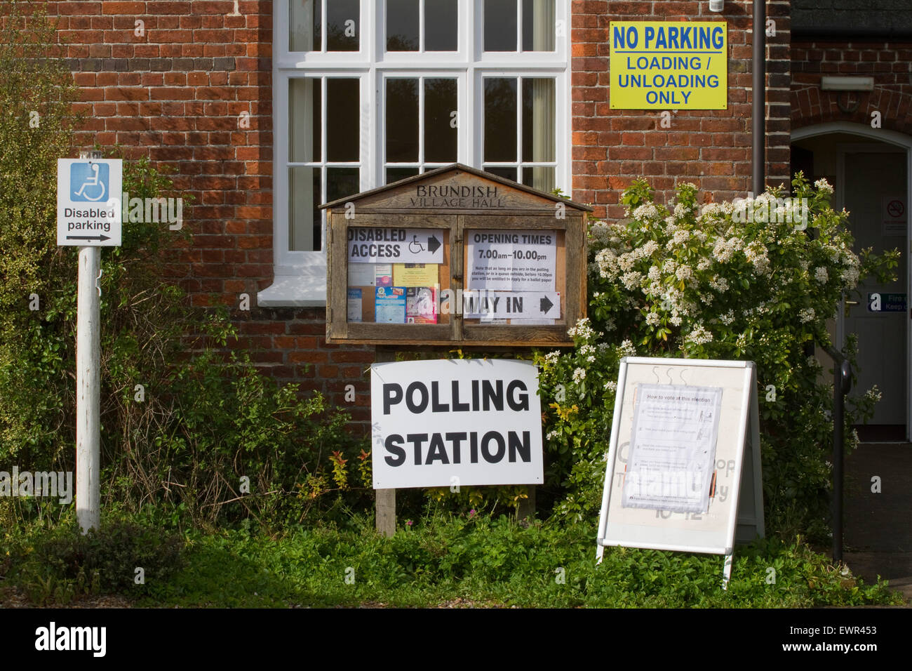 Une pléthore de signes à l'extérieur d'un village hall Suffolk utilisé comme bureau de scrutin pour une élection générale Banque D'Images