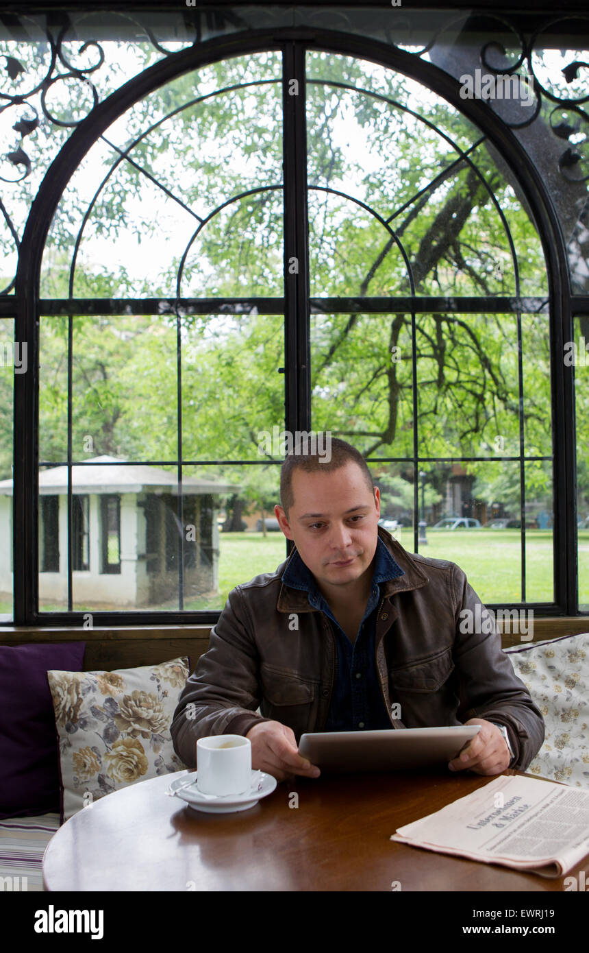 Un homme heureux de lire un ebook dans un café terrasse tenant une tasse de café Banque D'Images