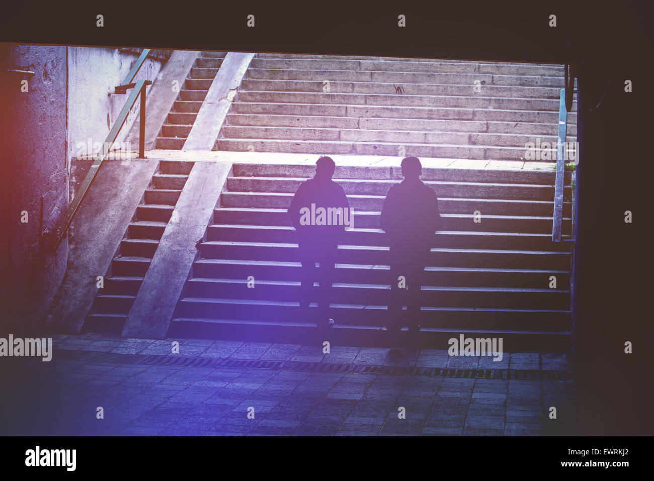 Les gens dans l'environnement urbain, les piétons circulant dans un passage souterrain, les silhouettes des deux femmes escalier en béton d'escalade Banque D'Images